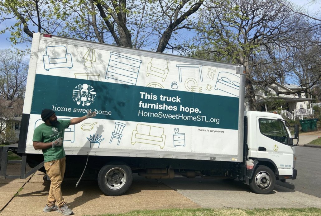 A Home Sweet Home volunteer beside the delivery truck that reads: this truck furnishes hope