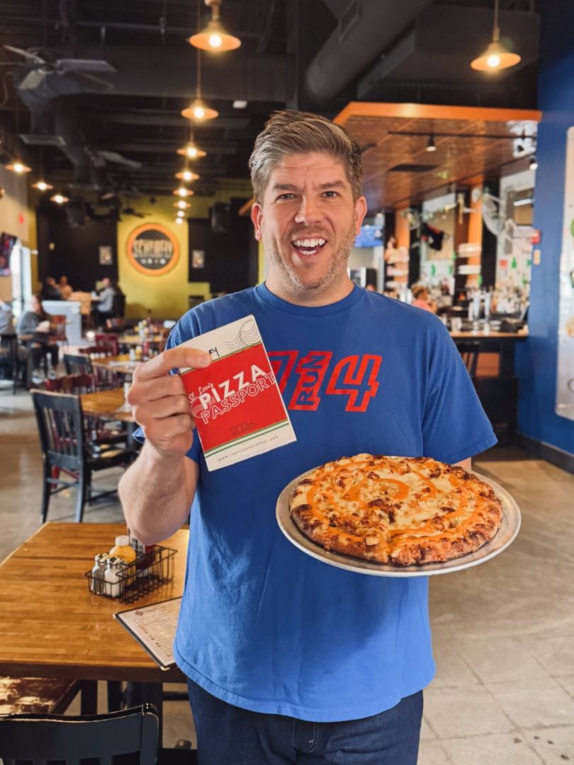 A passport holder at the table with his pizza and his book